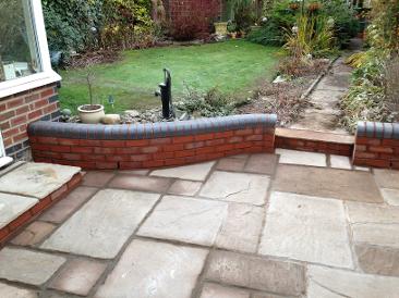 natural stone patio with blue double bullnose topped wall and step